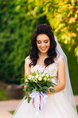 bride on a background of trees holding a wedding bouquet and smi