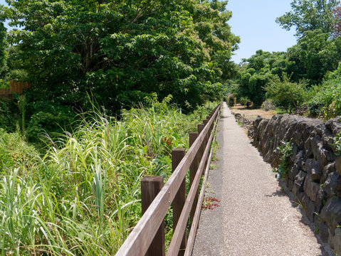 Long footpath with wooden fence next to the Tajima river leading to the Jogasaki coast in Ito, Izu, Japan.