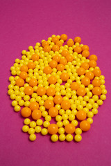 bunch of colorful pills for viral diseases. Prevention of influenza, coronavirus, covid-19. handful of yellow, orange vitamins on purple background. medical healthcare concept of virus protection