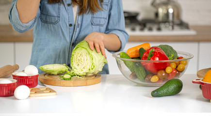 A young woman is preparing a salad in the kitchen .