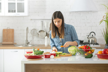 A young woman is preparing a salad in the kitchen .