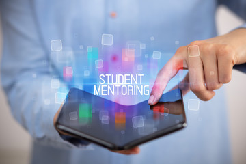 Young man holding a foldable smartphone with STUDENT MENTORING inscription, educational concept