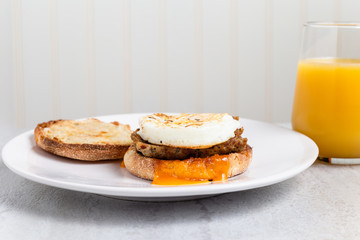 Egg, sausage and cheese breakfast sandwich with orange juice