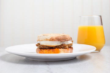 Egg, sausage and cheese breakfast sandwich with orange juice