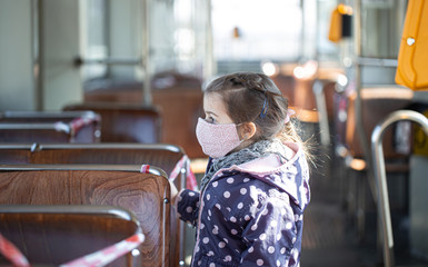 A little girl in an empty public transport during the pandemic.