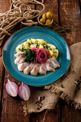 Appetizer, sliced fish on a platter on the table in the restaurant, on a wooden table, near burlap, rope.