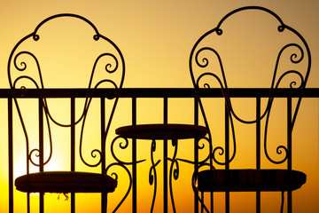 A Chairs silhouette at sunset near the sea. On nature, antique red-hot products.