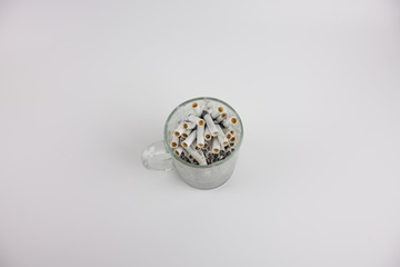 Cigarette butts in a mug on a white background