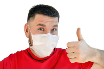 young man in a medical mask with a positive cheerful look and a thumbs up protects himself from viruses