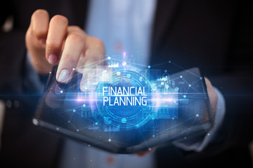 Young man holding a foldable smartphone with FINANCIAL PLANNING inscription, educational concept