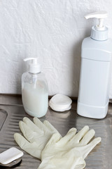 Latex gloves, liquid soap in bottle on metal surface.