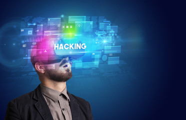 Businessman looking through Virtual Reality glasses with HACKING inscription, innovative security concept