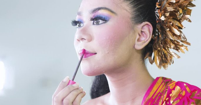 Pretty balinese dancer applying lipstick on her lips