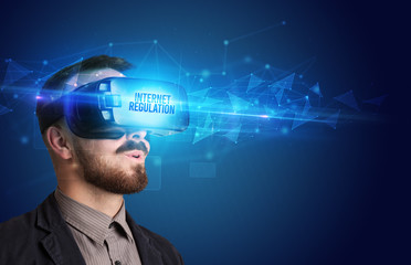 Businessman looking through Virtual Reality glasses with INTERNET REGULATION inscription, cyber security concept