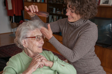 Senior woman gets her hair styled by caregiver 