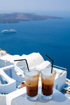 Two glasses of cold coffee in Santorini island. Traditional Greek Freddo cappuccino and sea view.