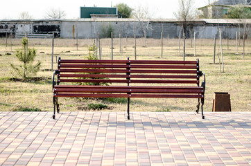 Bench in a city park. Brown bench made of wood. A place to relax.