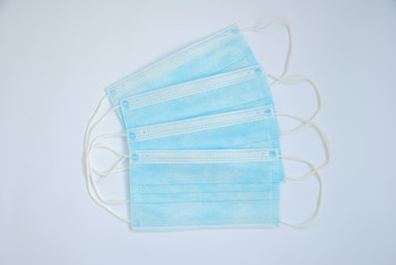 Medical surgical masks lying on a white background. Surgical masks with rubber ear straps. Typical 3-ply surgical masks to cover the mouth and nose. Procedure masks from bacteria. Protection concept.