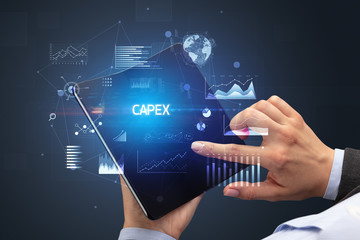 Businessman holding a foldable smartphone with CAPEX inscription, successful business concept