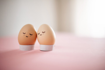 Two little easter eggs with a painted drawn happy faces on them in standing on the table isolated. Easter holidays decorations and preparations concept. Holy religious day. Copyspace, place for text.