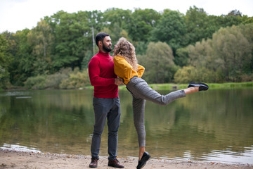 Young couple hold hands looking at each other on lake shore