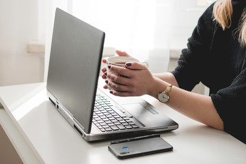 A person working remotely at home during quarantine. In the picture there is a laptop, desk, window and employee. Coronavirus 2020