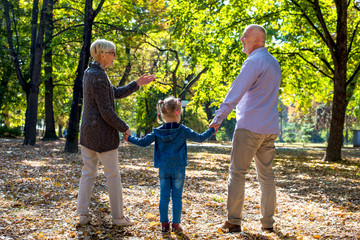 Happy grandparents enjoying the day with granddaughter while walking together