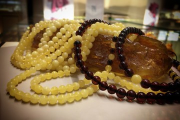 A lot of Baltic amber white beads lie on a large piece of natural amber. Template for decorating a jewelry store and a salon of expensive jewelry.