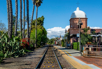 A single set of train tracks leads to a vanishing point on the horizon at the San Juan Capistrano train station.