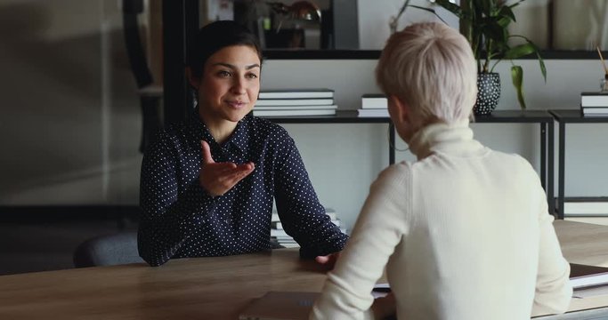 Happy successful indian candidate getting hired after good job interview handshaking female employer. Hr manager employing applicant, selling insurance to client, shaking hand of new company recruit.