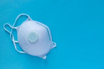 White medical mask , protective mask with filter class FFP1 , on a blue background , close-up, with empty space for notes . Protective mask protects against  virus diseases 