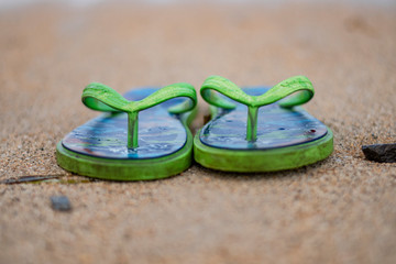 Fototapeta na wymiar A pair of slippers in a seaside with sands in a tranquil exotic weather during the summer in Bali