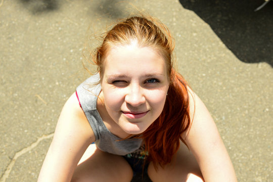 Portrait of a charming red-haired girl looking happily up and smiling joyfully