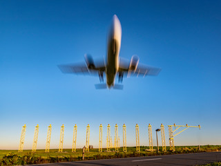 A plane about to land during sunrise/sunset under a blue sky. Speed, motion effect.