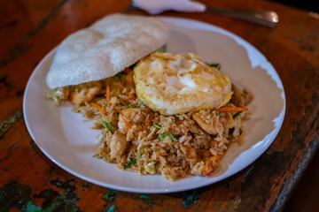 Balinese dinner served in a white plate with mixed seafood friedrice and egg