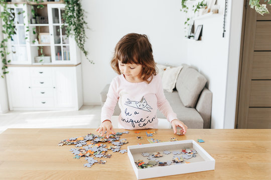 Toddler girlplaying puzzles at home. Stay at home activity for kids.