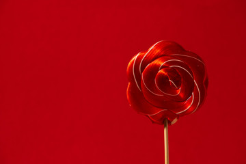 red candy caramel on a stick on a red background