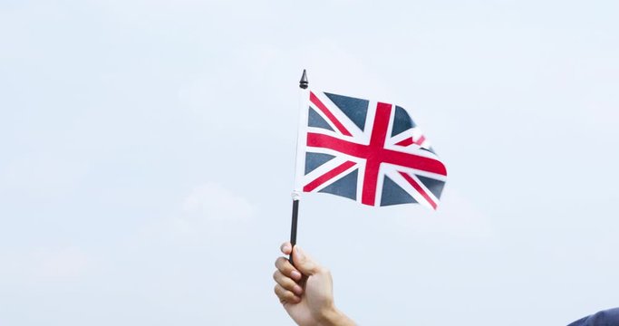 Unknown hand holding a waving United Kingdom flag