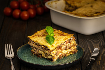Classic Italian lasagna piece at plate on wooden table, healthy food