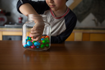 child takes chocolates from the transparent  jar