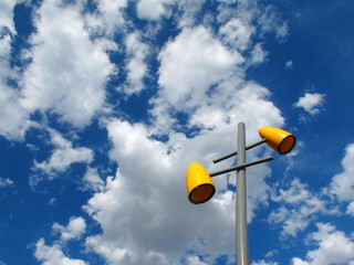 yellow lamp on the light pole in front of blue sky have white cloud