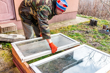 Man working on diy project construction closeup of vegetable winter garden for raised bed cold frame box in Ukraine dacha by farm house
