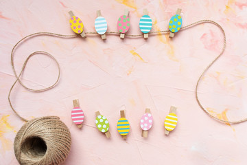 Pastel and gold colored eggs decoration pinned on a rope on a pastel pink background. Easter celebration concept. Top view, flat lay, copy space