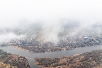 Nowy Dwor, Poland aerial above high angle view from window near airport with rural winter brown landscape countryside near Warsaw and river by farm fields and clouds fog mist