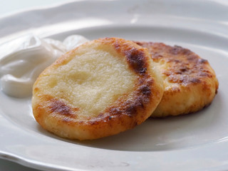 Cottage cheese pancakes are on a plate. Toasted cottage cheese pancakes with a Golden crust lie on a white plate