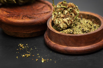 Close up of green dried marijuana bud lying at the top of wooden grinder