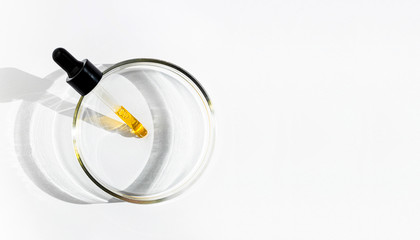 A liquid yellow serum or oil in a dropper on white background with copy space. Natural cosmetic....