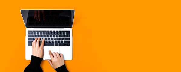 Person using a laptop computer on a solid color background - obrazy, fototapety, plakaty