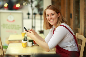 young woman sitting at a coffee shop with her phone
