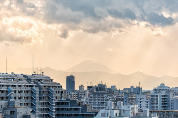 Sunset in Tokyo, Japan Shinjuku cityscape with silhouette view of Mount Fuji and golden sunlight, apartment buildings and mountains with rain clouds